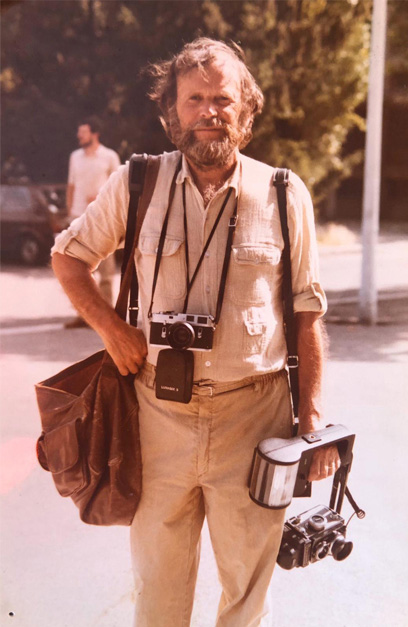 Portrait d'André Gobeli, appareils photo en bandoulière
